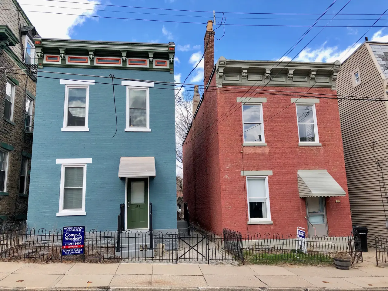The image shows a row of colorful houses on the corner of a street, with windows and doors, a metal...