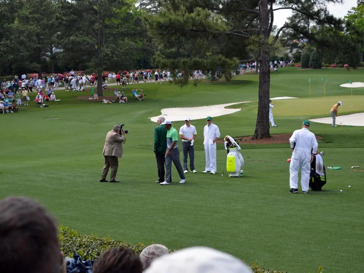 In this image there are a few people playing golf on the golf course, besides them there are kits,...