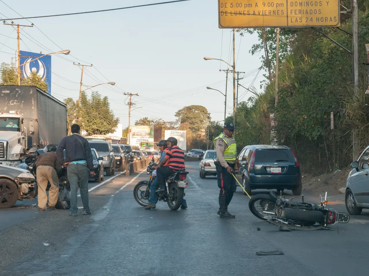 The image shows a group of people standing around a motorcycle that has been involved in a crash on...