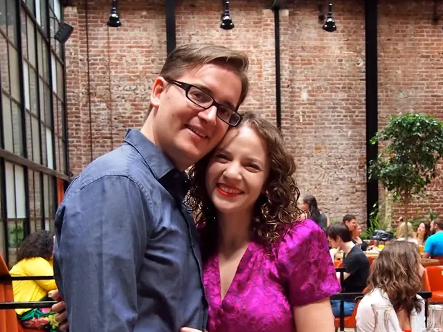 In the picture we can find a man and a woman they both are smiling. In the background we can find a...