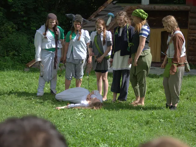 In the picture there is a group of women standing beside a person laying on the grass, she is shot...