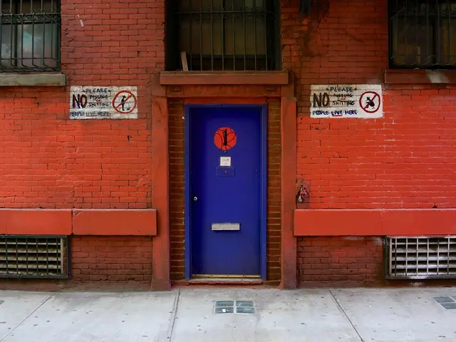 In the foreground of this image, there is a pavement. In the background, there is a red building...