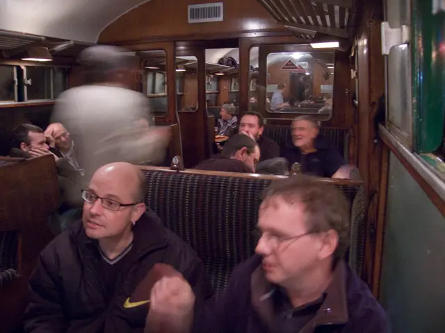 This picture is taken inside the train. At the bottom, there are two men sitting on the seat....