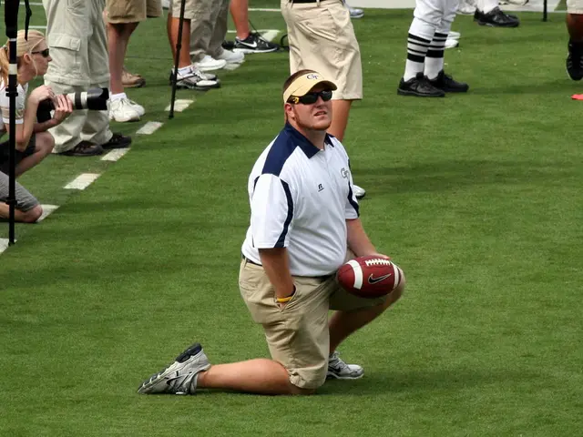 Here in the center we can see a man kneeling down with rugby ball in his hand and at the left side...