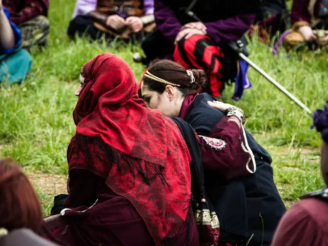 In this image I can see a group of people are sitting on grass, handbags and stick. This image is...