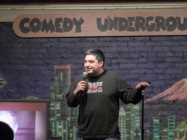 This picture shows a man standing and speaking with the help of a microphone in his hand and we see...