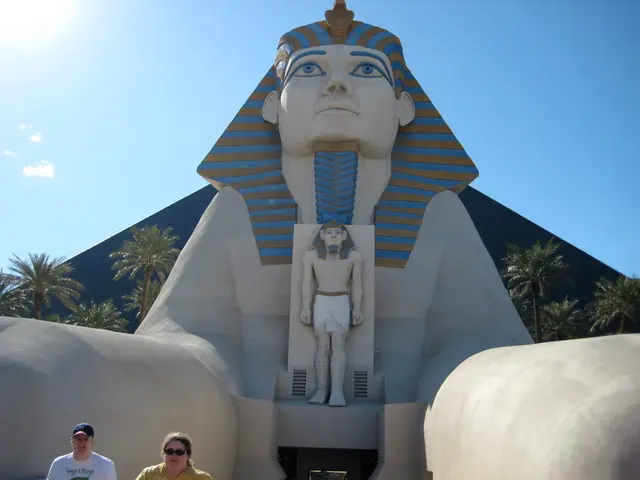 In the foreground of this image, there is an Egypt sculpture and there are two persons on the...