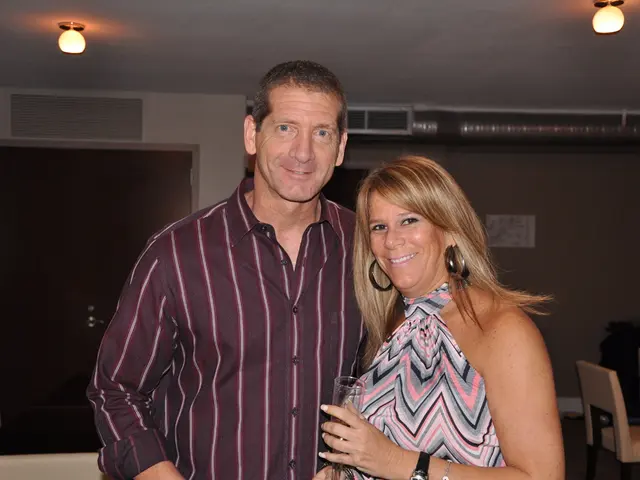 In the image there is a man and woman standing in the front smiling, it seems to be clicked in a...