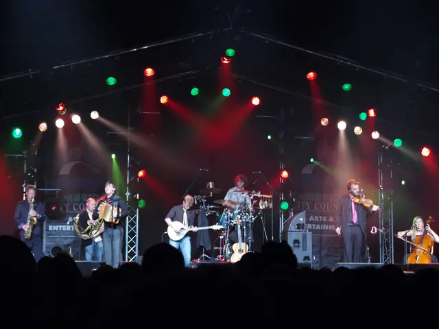 In a picture people are standing and performing on the stage in front of the crowd and coming to...