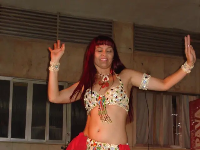 In the image there is a woman in gown doing belly dance and behind her there are windows on the...