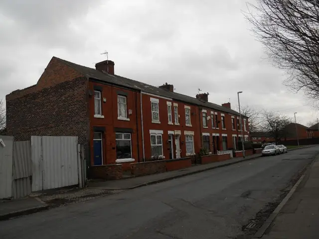 Sky is cloudy. Here we can see buildings, glass windows, bare trees, light poles and vehicles.