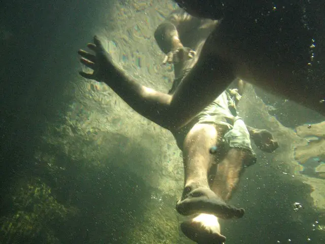 In the image I can see two people who are in the water.