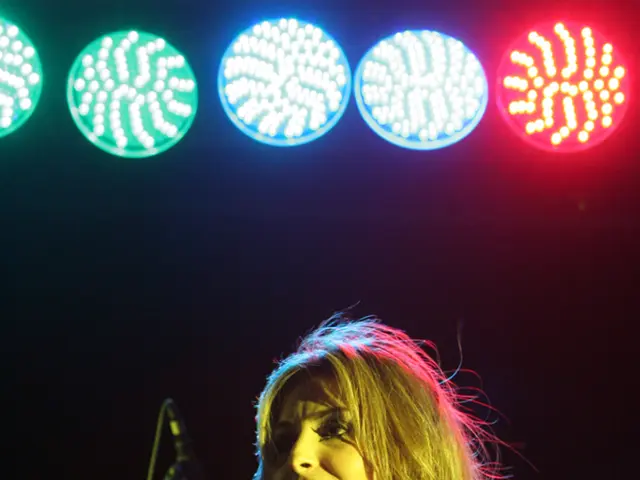 Here we can see a woman singing with a microphone in her hand and above her there are colorful...