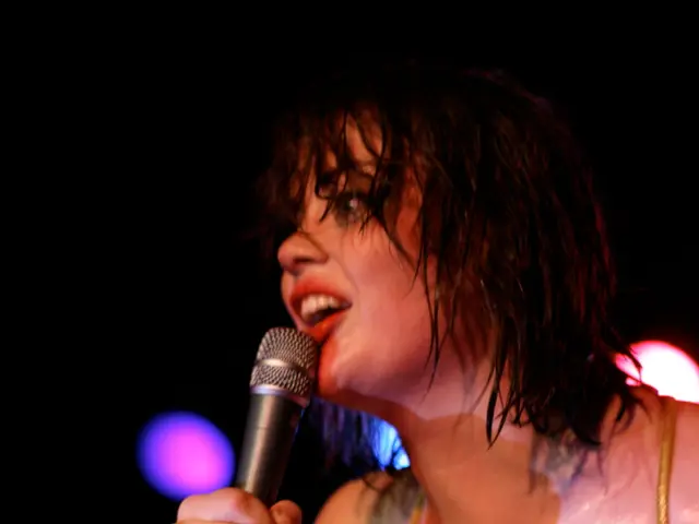 This picture is clicked in a musical concert. There is a woman who is holding a microphone in her...