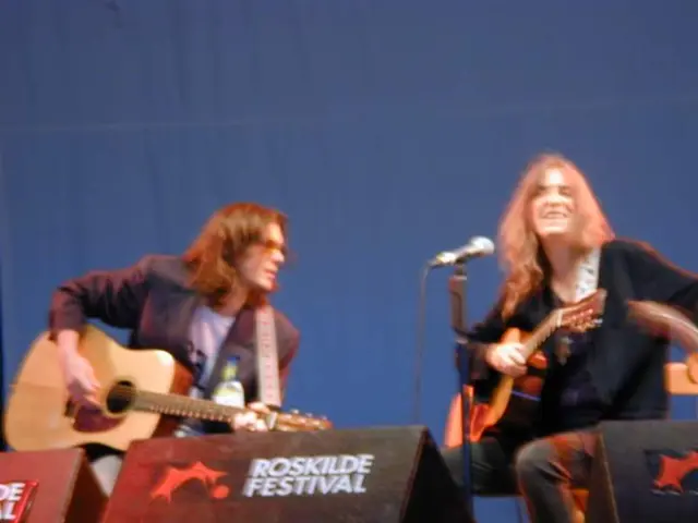 In this picture two guys are on stage with musical instruments on stage , there is also a mic...