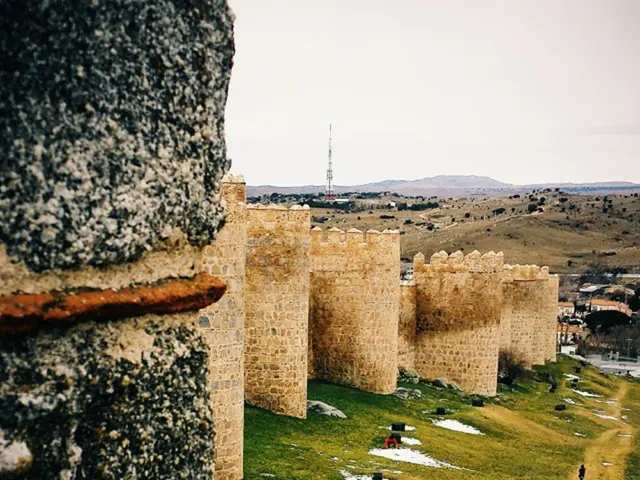 In this image we can see a fort. In the background there are hills, tower and sky. At the bottom...