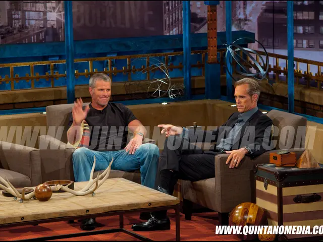 It is a media interview there are two people sitting on the sofa adjacent to each other in front of...