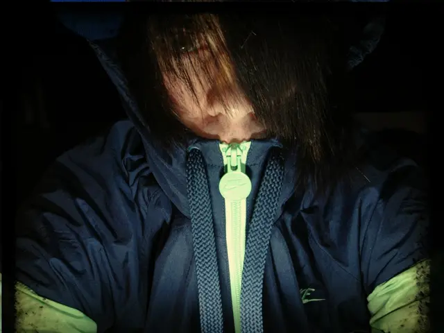 In this image I can see a person wearing a jacket, looking at the picture and the hair falls on the...