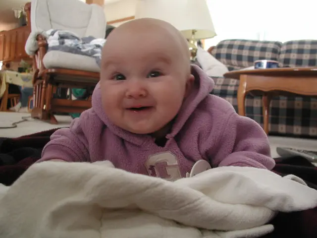 This picture is taken inside the house where a boy is seeing smiling. In the background there is a...