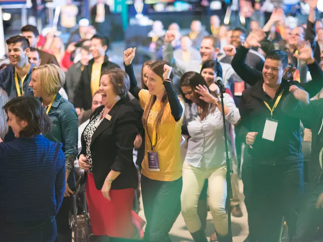 In the center of the image we can see many people standing and laughing. There is a mic placed on...