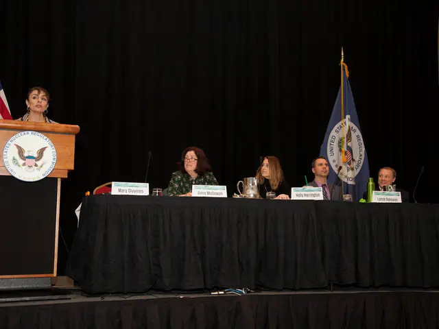In this image we can see a woman is standing on the stage at the podium and there is a round board...
