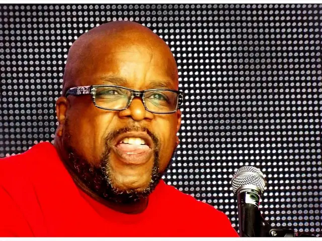 In this image, we can see a person wearing spectacles. We can also see a microphone. We can see the...