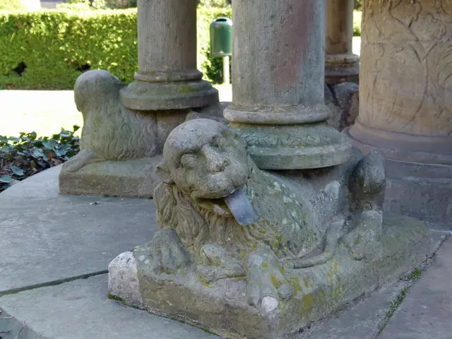 In this image there are poles and depiction of lions. In the background there are trees and leaves...