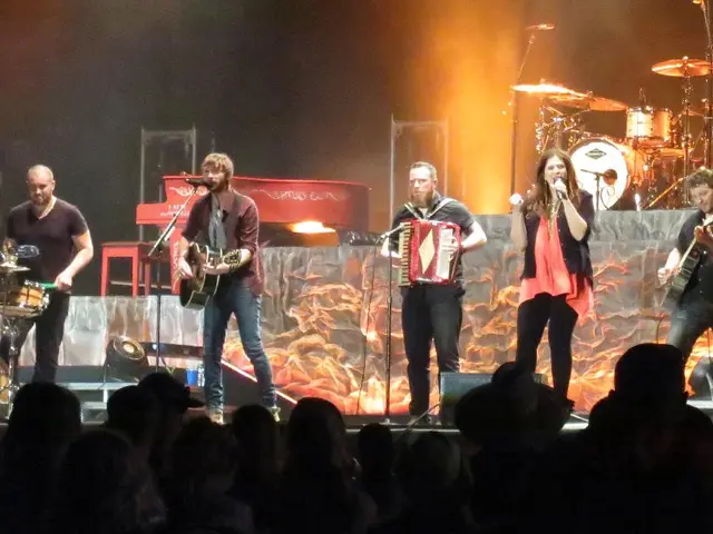 There are group of people playing music and two among them is singing in front of a mic, In...