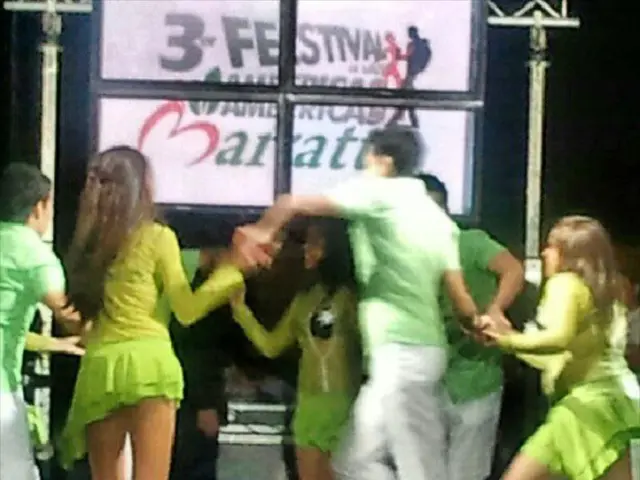 There are persons in different color dresses giving a performance on a stage on which, there are...