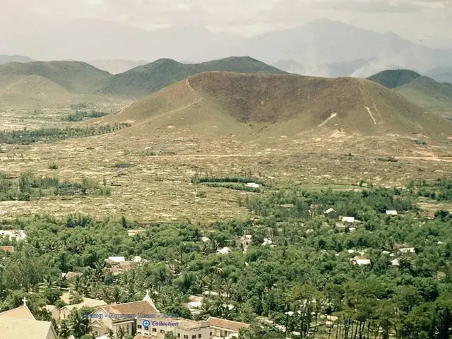 In the foreground of this image, there are mountains, city, trees, sky and the cloud.