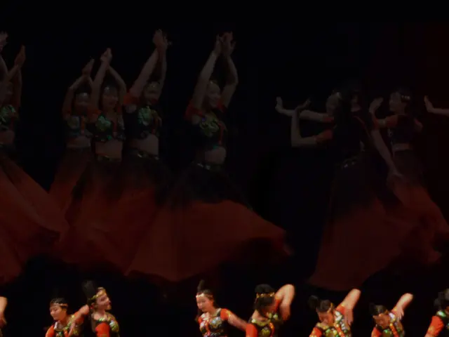In this picture we can see the group of girls wearing red color dresses and dancing on the stage....