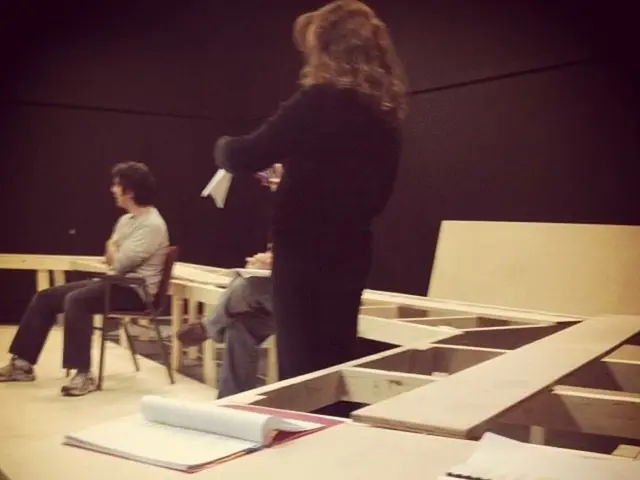 In this image I can see three people and there are some books.