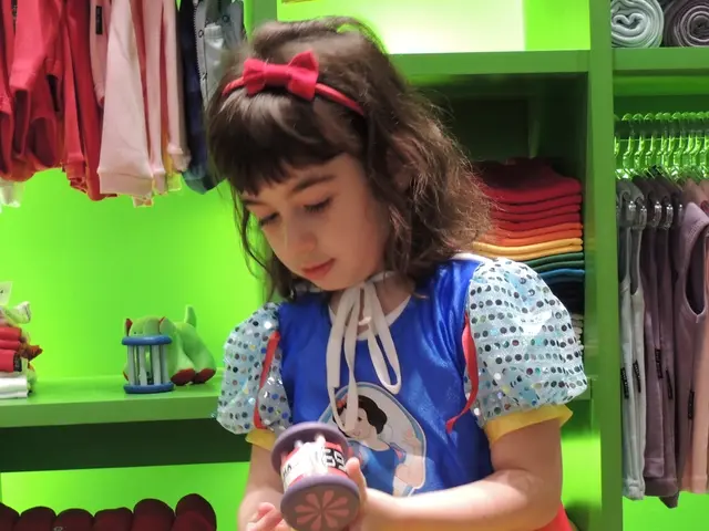 In this picture I can see a girl is wearing a frock. The girl is sitting on an object and holding...