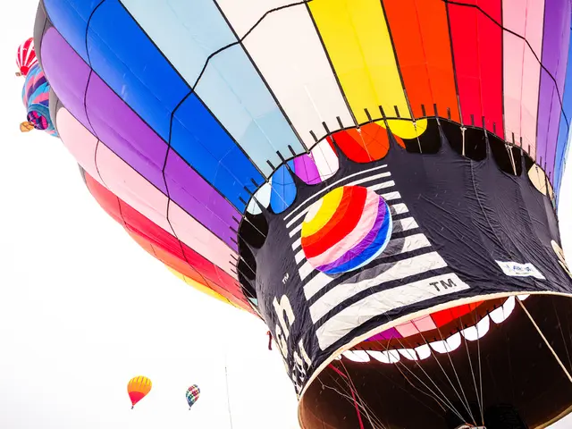 In this picture, we see three hot air balloons which are in blue, pink, white, yellow, red, orange...