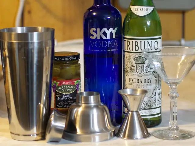 In this image we can see some bottles, glasses, a jar and an antique which are placed on the table.