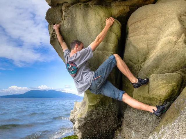 In this image we can see a person climbing a mountain. On the left side, we can see the water,...