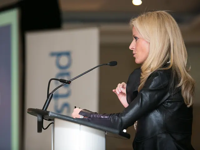 In the foreground of the picture there is a woman in black dress talking, in front of her there is...