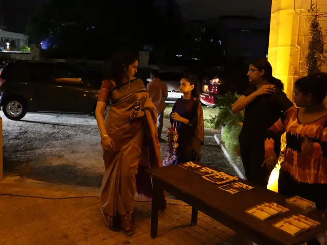 There is woman who is wearing a sari and holding a purse. On the bottom right corner there is a...