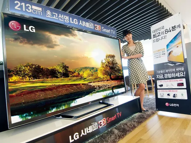 The woman in white and black dress is standing beside the television. Beside her, we see a smart...