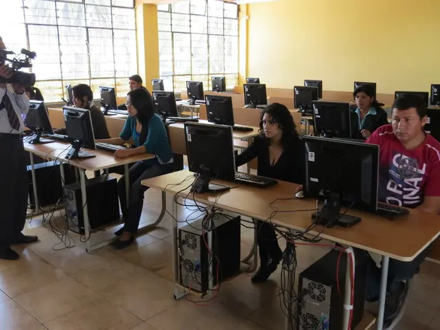 This is a classroom. There are few people sitting here, a group of people in front of monitors...