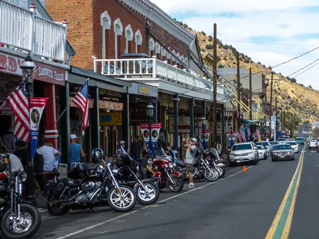 In the image we can see there are bikes and cars parked on the road. There are people standing near...