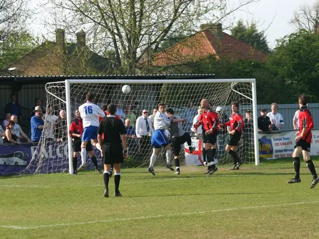 In this image we can see players are playing football in the ground. Behind goal net is there and...