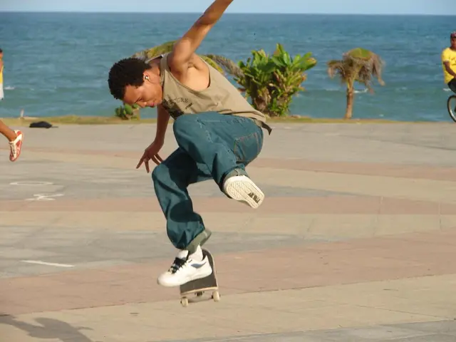 In this image in the center there is a person performing stunt on skating board. In the background...