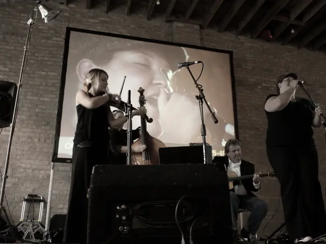 In this picture there are many musicians dressed in black among them a girl is playing violin and...