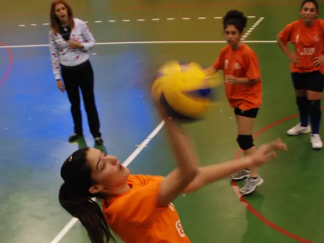 A woman volleyball player is hitting the ball. Two other players are watching her along with...