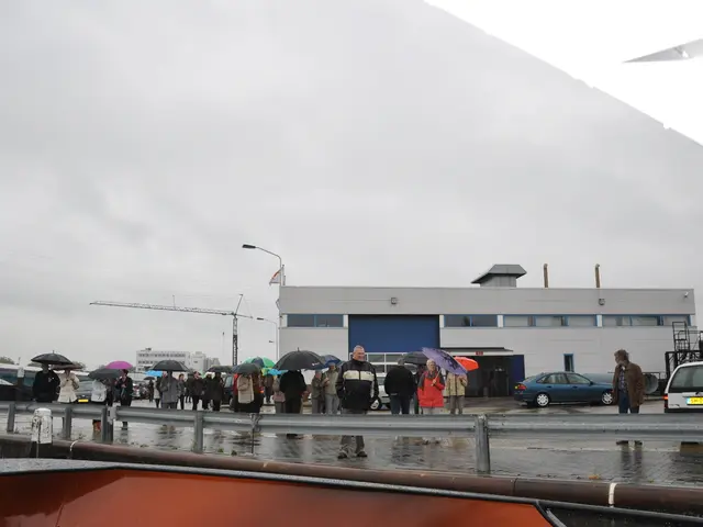 There are groups of people standing and few people are holding umbrellas. This is the flag hanging...