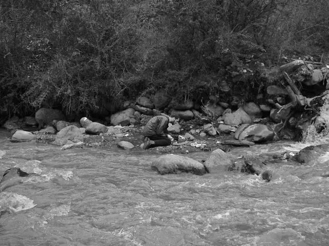 In this image there is a water flow, beside the water flow there is a person kneeled down on the...