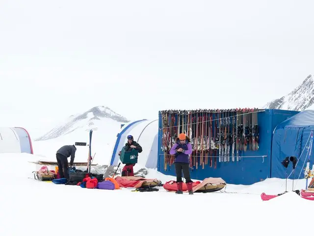 In the image there are three standing on the ice land with bags all over the place and behind them...