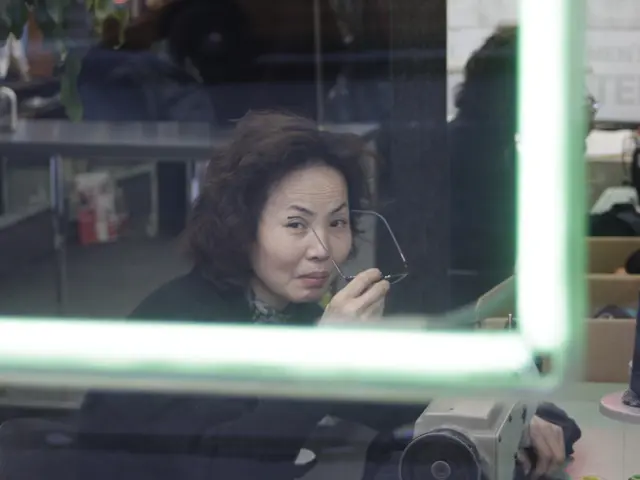 In the image there is a woman sitting in front of table with sewing machine in front of her and...