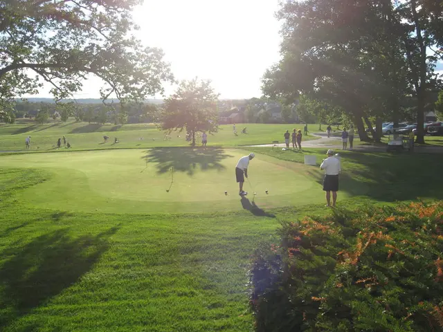 This picture was taken in the gold court. There are groups of people standing. This man is holding...